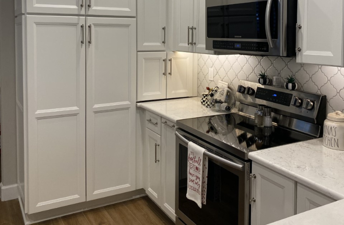 white cabinets custom tile backsplash and wood flooring in kitchen with stone countertops