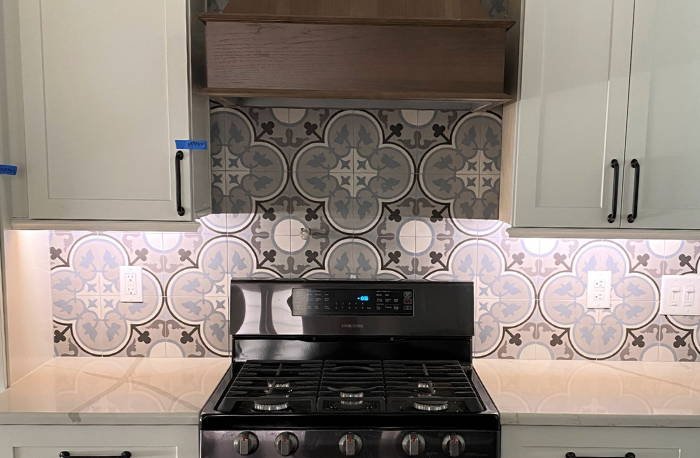 white cabinets with stone countertops and custom tile backsplash with wood oven hood vent